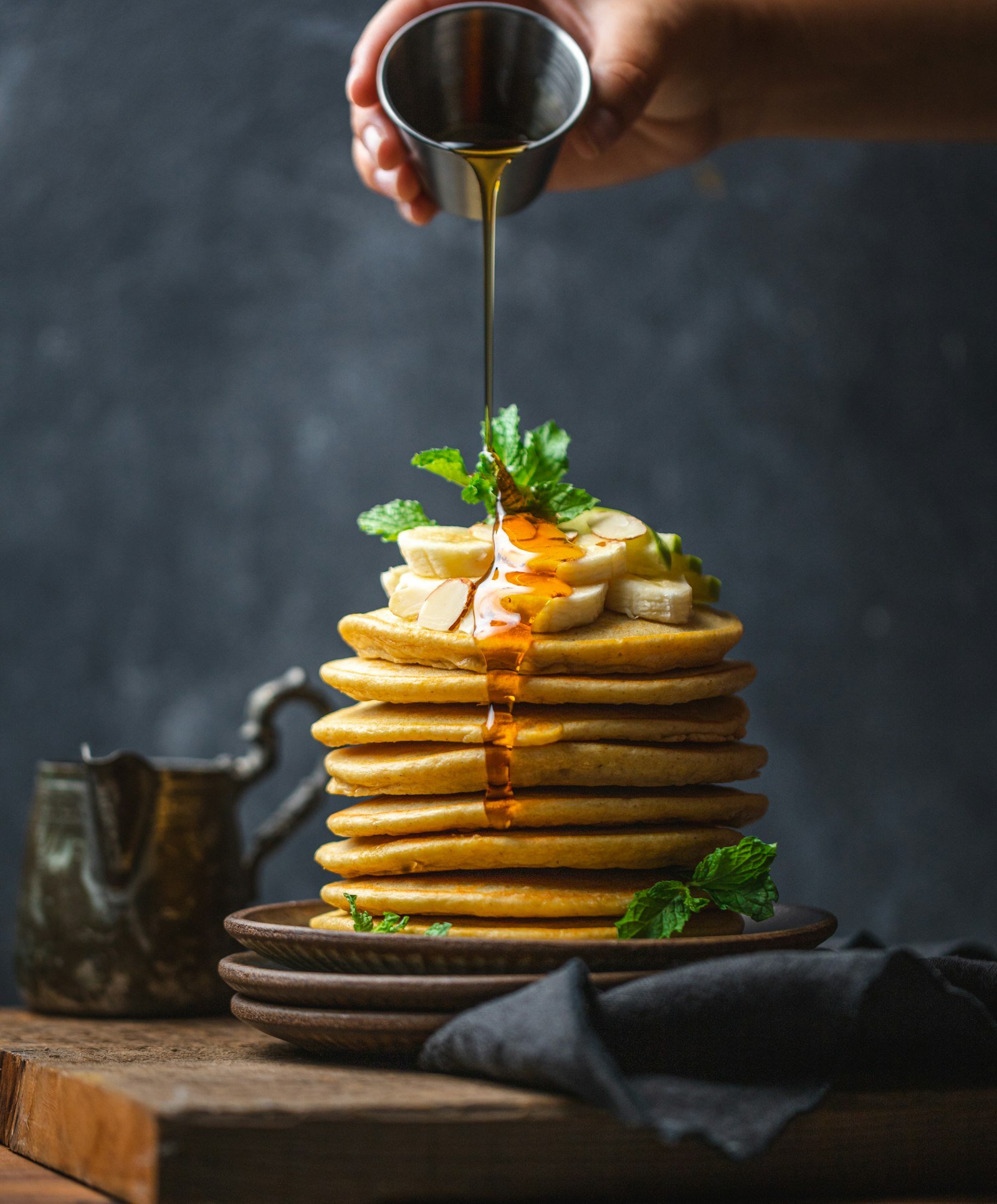A tall stack of fluffy buttermilk pancakes with maple syrup.